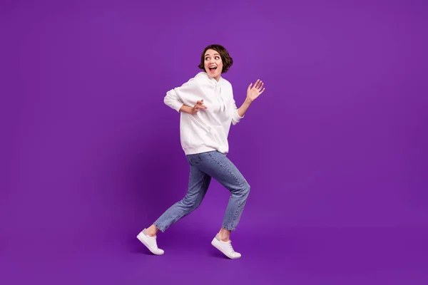 Photo pleine grandeur de jeune fille joyeuse funky fuyant vêtements ludiques pull blanc isolé sur fond de couleur violette — Photo