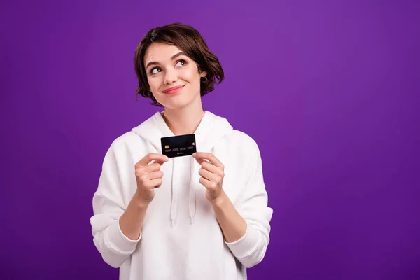 Foto de joven hermosa niña sonriente mirada copyspace mantenga la tarjeta de crédito aislada sobre fondo de color violeta —  Fotos de Stock