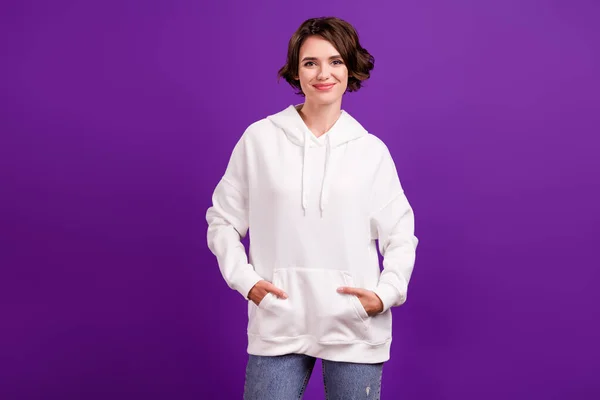 Foto de dulce encantadora mujer joven vestida de blanco pullover brazos bolsillos sonriendo aislado color violeta fondo — Foto de Stock