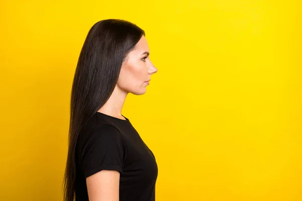 Sakin, ciddi, odaklanmış bir kadının profil fotoğrafı boş görünüyor. Siyah tişört, izole edilmiş sarı arka plan. — Stok fotoğraf