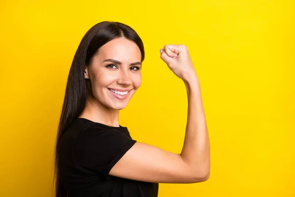 Photo de profil de charmante dame satisfaite bras flexion montrant biceps regarder caméra isolé sur fond de couleur jaune — Photo