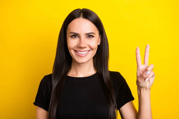 Portré gyönyörű elégedett lány sugárzó mosoly néz kamera ujjak mutatják v-jel elszigetelt sárga színű háttér — Stock Fotó