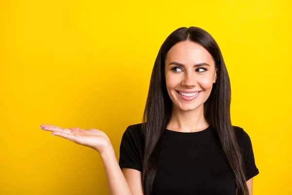 Retrato de encantadora persona positiva mirada mano interesada palma mantenga vacío el espacio aislado sobre fondo de color amarillo —  Fotos de Stock