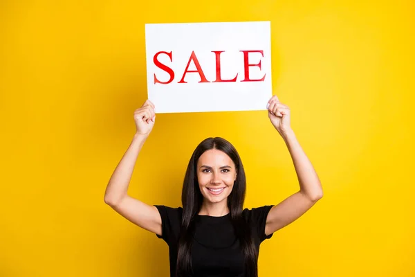 Photo of charming positive girl hands hold sale poster above head toothy smile isolated on yellow color background — Stock Photo, Image