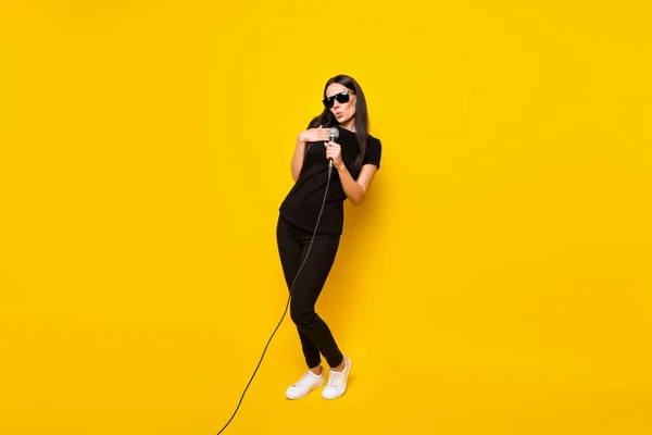Teljes hosszúságú fotó izgatott pozitív lány kar tartsa mikrofon izgatott éneklés elszigetelt sárga színű háttér — Stock Fotó