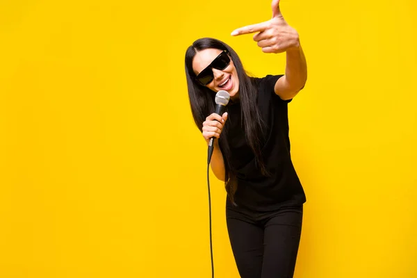 Foto de louco satisfeito pessoa apontar dedo segurar microfone desfrutar de cantar isolado no fundo de cor amarela — Fotografia de Stock