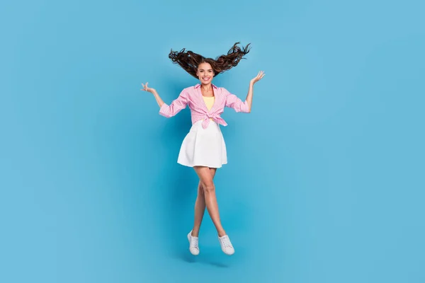 Фото довольно милой молодой леди носить розовую рубашку прыгая высоко поднимая руки руки улыбаясь изолированный синий цвет фона — стоковое фото