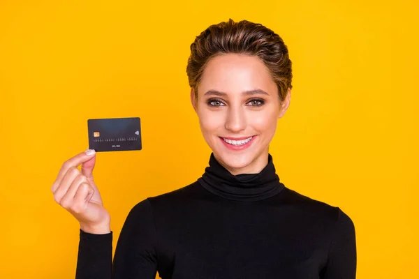 Retrato de chica alegre atractiva sosteniendo en la mano depósito de la tarjeta bancaria aislado sobre fondo de color amarillo brillante —  Fotos de Stock