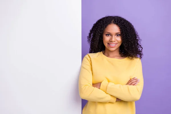 Foto de chica de piel oscura bastante segura vestida sudadera amarilla brazos cruzados espacio vacío sonriendo aislado color púrpura fondo — Foto de Stock