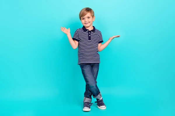 Pleine longueur photo de mignon petit garçon tenir vide espace porter t-shirt jeans baskets isolé sur fond de sarcelle — Photo