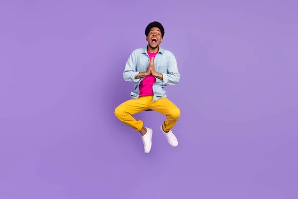Foto de agradecido agradecido chico salto súplica agarre de las manos usar azul camisa pantalones zapatos aislados color púrpura fondo — Foto de Stock