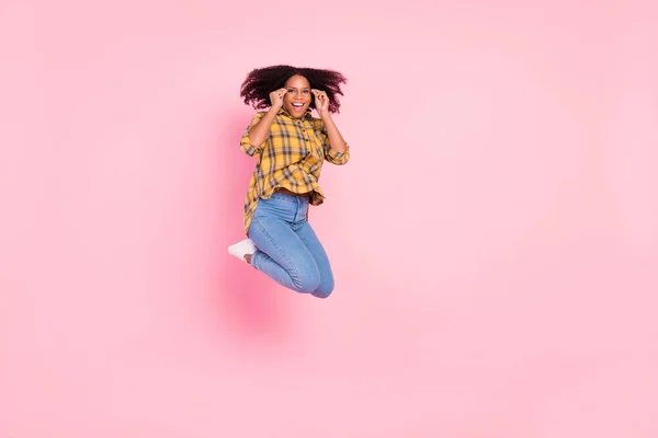 Foto de surpreendido animado salto senhora desfrutar de voo desgaste xadrez camisa jeans tênis isolado cor-de-rosa fundo — Fotografia de Stock