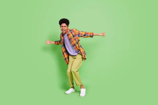 Foto de homem de pele escura doce funky usar camisa xadrez sorrindo dançando isolado fundo cor verde — Fotografia de Stock