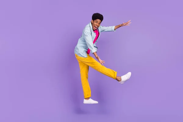 Foto do promotor cara pular braços segurar espaço vazio usar calças camisa azul sapatos isolado cor roxa fundo — Fotografia de Stock