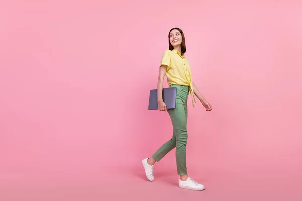 Perfil de tamaño completo lado de la foto de la joven sonrisa feliz ir curioso mirar espacio vacío mantenga el ordenador portátil aislado sobre fondo de color rosa —  Fotos de Stock