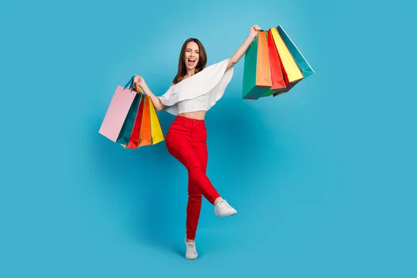 Foto van glanzende verlaten jonge dame dragen off-schouders shirt wandelen holding shopping tassen glimlachen geïsoleerde blauwe kleur achtergrond — Stockfoto