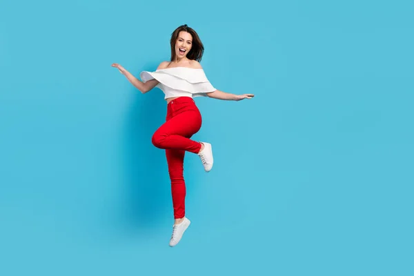 Full size foto van zoete brunette jonge dame springen slijtage blouse jeans geïsoleerd op blauwe kleur achtergrond — Stockfoto