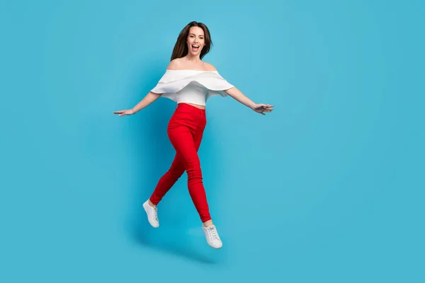 Foto de adorável impressionado jovem mulher vestida blusa branca sorrindo saltando alto espaço vazio isolado fundo de cor azul — Fotografia de Stock