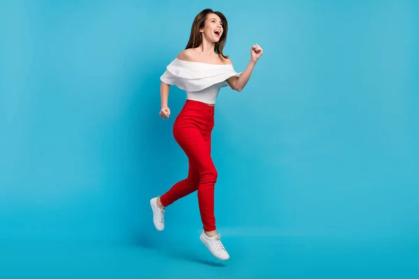 Photo impressionnée femme funky habillé chemisier blanc souriant sautant courir regardant vide espace isolé fond de couleur bleue — Photo