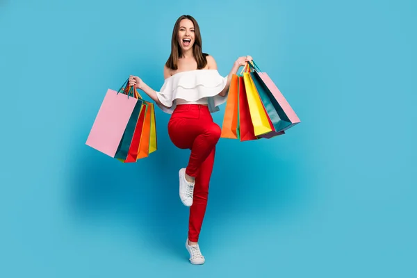 Helkroppsfoto av ganska förvånad glad kvinna hålla händer shoppingväska vinnare isolerad på blå färg bakgrund — Stockfoto