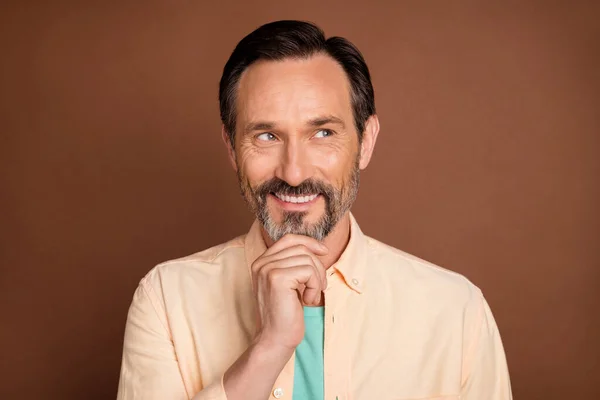 Photo of age brunet man look empty space wear brzoskwiniowa koszula izolowana na brązowym tle — Zdjęcie stockowe