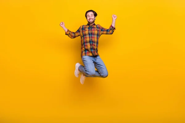 Full body photo of funny brunet young guy jump wear shirt jeans sneakers isolated on yellow background — Stock Photo, Image