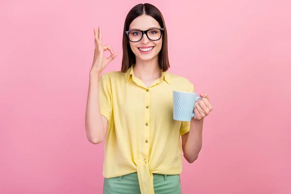 Foto da menina feliz sorriso positivo mostrar tudo bem símbolo recomendo xícara de café isolado sobre fundo cor-de-rosa — Fotografia de Stock