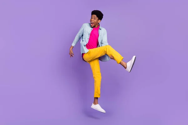 Foto de chico inspirado salto agarre pierna imaginar jugar guitarra desgaste azul camisa pantalones zapatos aislados color púrpura fondo — Foto de Stock