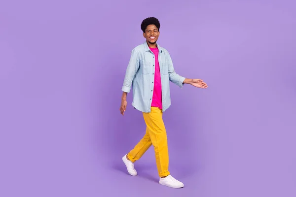 Foto de encantador homem de pele escura usar camisa jeans sorrindo andando isolado cor roxa fundo — Fotografia de Stock