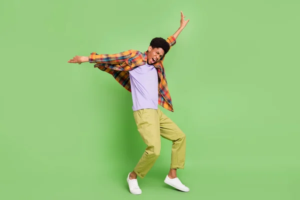 Foto de engraçado muito escuro cara pele vestido camisa xadrez dançando braços lados sorrindo isolado cor verde fundo — Fotografia de Stock