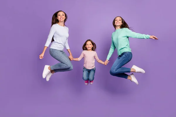 Pleine longueur taille du corps vue de trois jolies filles gaies à la mode sautant mains tenues isolées sur fond violet vif de couleur — Photo