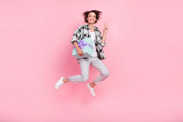 전체 길이의 프로필 사진 행복 한 미소 점프젊은 여자가 현재 박스 쇼 v-sign 을 개최 핑크 색 배경에 분리 — 스톡 사진