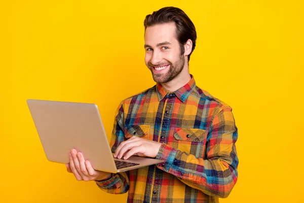 Fotografie pohledný roztomilý mladý chlap oblečený kostkovaná košile pracovní moderní ganget úsměv izolované žluté barvy pozadí — Stock fotografie