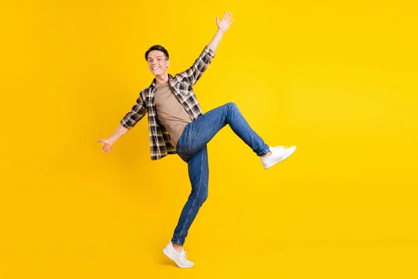 Çılgın kaygısız funky adamın fotoğrafı dans etmeyi seviyor ekose gömlekli kot pantolon giyiyor izole edilmiş sarı arka plan — Stok fotoğraf