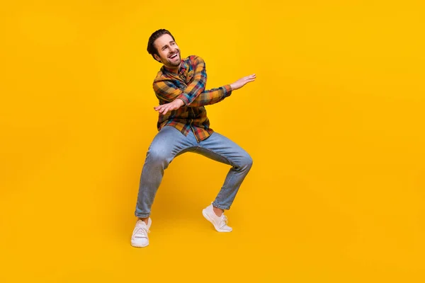 Ganzkörperfoto von schönen brünetten jungen Kerl Tanz tragen Hemd Jeans Turnschuhe isoliert auf gelbem Hintergrund — Stockfoto