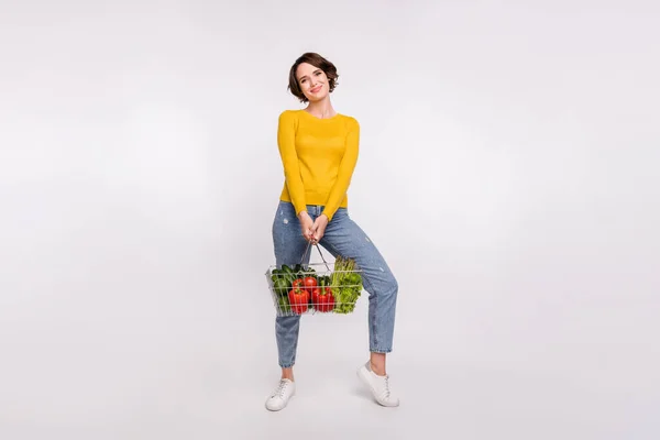 Foto em tamanho completo de linda morena milenar senhora segurar alimentos desgaste camisa amarela jeans isolado no fundo de cor cinza — Fotografia de Stock