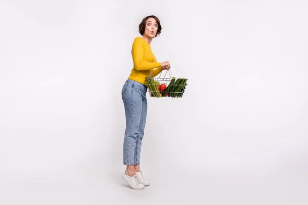 Foto av galen förvånad flicka stå tå håll mat korg bära gul skjorta isolerad grå färg bakgrund — Stockfoto