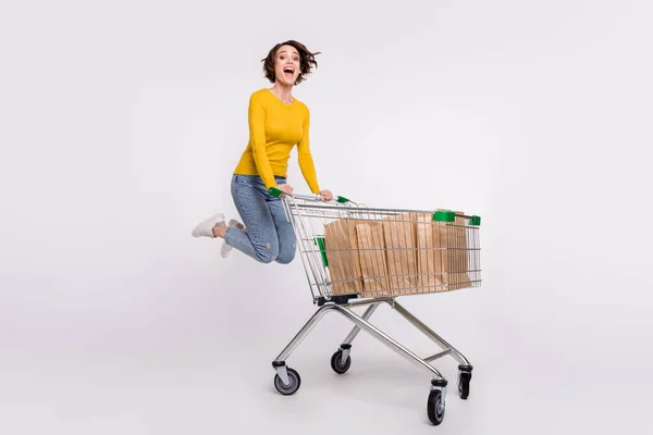 Full length φωτογραφία του αστεία μελαχρινή νεαρή κοπέλα κάνει ψώνια άλμα φορούν τζιν πουκάμισο απομονωμένο σε γκρι φόντο χρώμα — Φωτογραφία Αρχείου