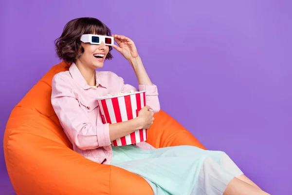 Photo of worried young woman sit chair look empty space tv 3d glasses movie isolated on violet color background — Stock Photo, Image