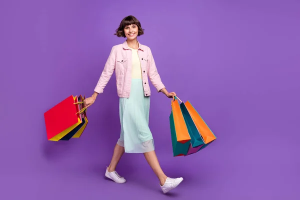 Pełna długość zdjęcie uroczej młodej kobiety spacer weekend trzymać ręce torby na zakupy izolowane na fioletowym tle koloru — Zdjęcie stockowe