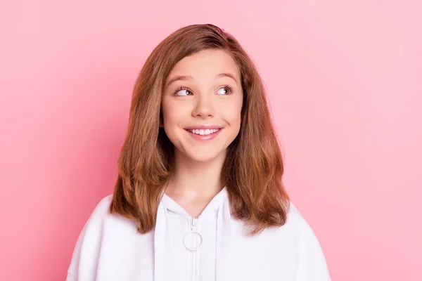 Foto de dulce encantadora colegiala vestida con sudadera blanca sonriendo buscando espacio vacío aislado color rosa fondo — Foto de Stock