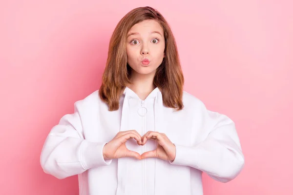 Foto retrato sonriente chica usando hodie mostrando señal de corazón enviando beso de aire aislado pastel color rosa fondo —  Fotos de Stock