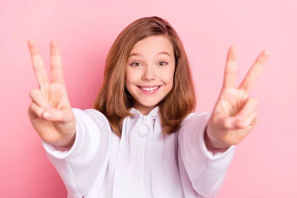 Foto di sognante adorabile piccola studentessa vestita felpa bianca che mostra v-segni sorridente isolato colore rosa sfondo — Foto Stock