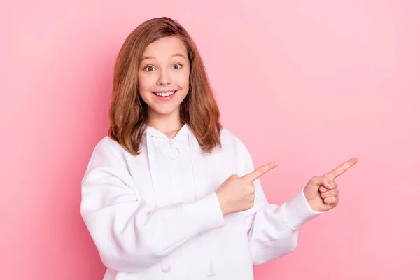 Foto retrato chica sonriente señalando los dedos espacio vacío recomendando aislado pastel color rosa fondo —  Fotos de Stock