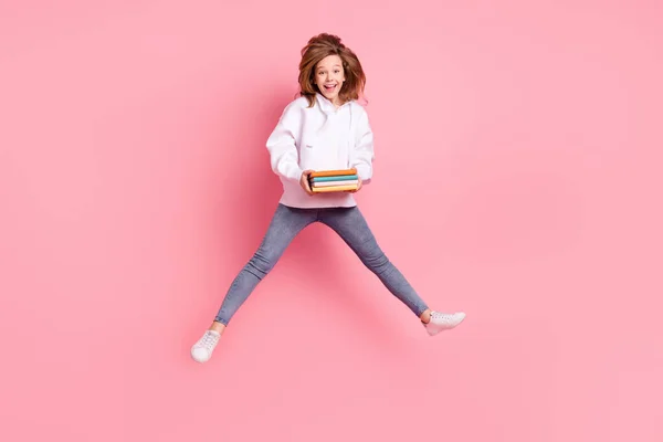 Full längd kropp storlek tillbaka visa flicka hoppa högt hålla bok stack skrattar isolerad pastell rosa färg bakgrund — Stockfoto