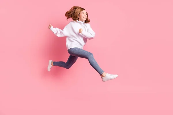 Foto de adorable linda colegiala pequeña vestida de sudadera blanca saltando corriendo buscando espacio vacío aislado color rosa fondo — Foto de Stock