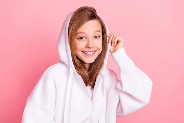 Foto portret klein meisje in witte hoodie glimlachen in kap geïsoleerde pastel roze kleur achtergrond — Stockfoto