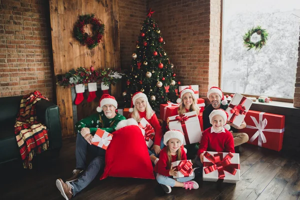 Porträtt av attraktiv glad familj spendera Eve Noel bär hattar sitter på golvet innehav presenter hemma loft hus inomhus — Stockfoto