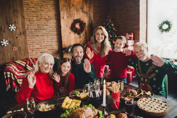 Gülümseyen aile fotoğrafı. Masada oturmuş Noel 'i el sallayarak kutluyoruz. — Stok fotoğraf