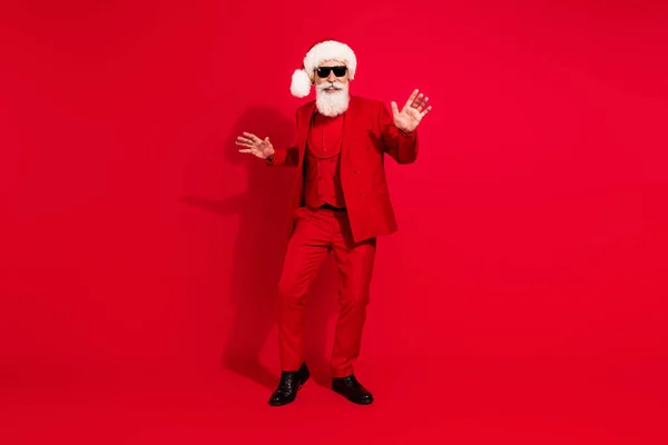 Foto von unbeschwerten Weihnachtsmann Tanz genießen Wochenende Party tragen Sonnenbrille X-mas Hut Anzug auf rotem Hintergrund — Stockfoto